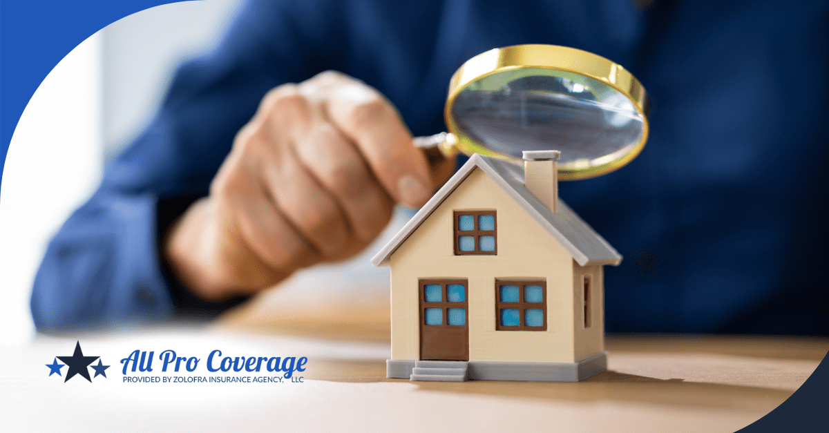 A close-up of a hand holding a magnifying glass over a small model house