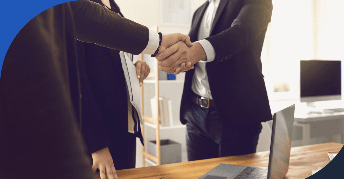 Business professionals shaking hands in a modern office, symbolizing a successful agreement or partnership.